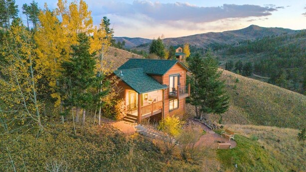 A two-story log cabin with a green roof, surrounded by trees and hills. - Pikes Peak Ranch - Elk Ridge Cabin (Woodland Park)