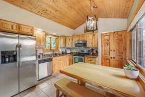 A kitchen with wooden cabinets, stainless steel appliances, a granite countertop, and a large window. - Pikes Peak Ranch - Elk Ridge Cabin (Woodland Park)