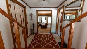 Un escalier en bois, recouvert d’un tapis à motifs, mène à un salon.