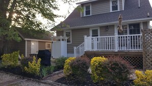Ein Wohnhaus mit Veranda, überdachter Grillanlage und verschiedenen blühenden Pflanzen.