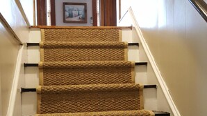 Eine Teppichstufen Treppe mit Handlauf und einem Bilderrahmen an der Wand oben.