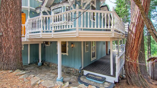 A two-story house with a balcony, stone steps, and a porch. - Chateau Royal East (Yosemite National Park)