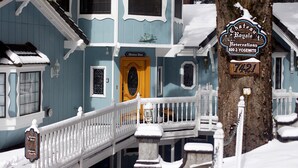 A snow-covered building with a sign indicating Chateau Royale Reservations and a phone number. - Chateau Royal East (Yosemite National Park)