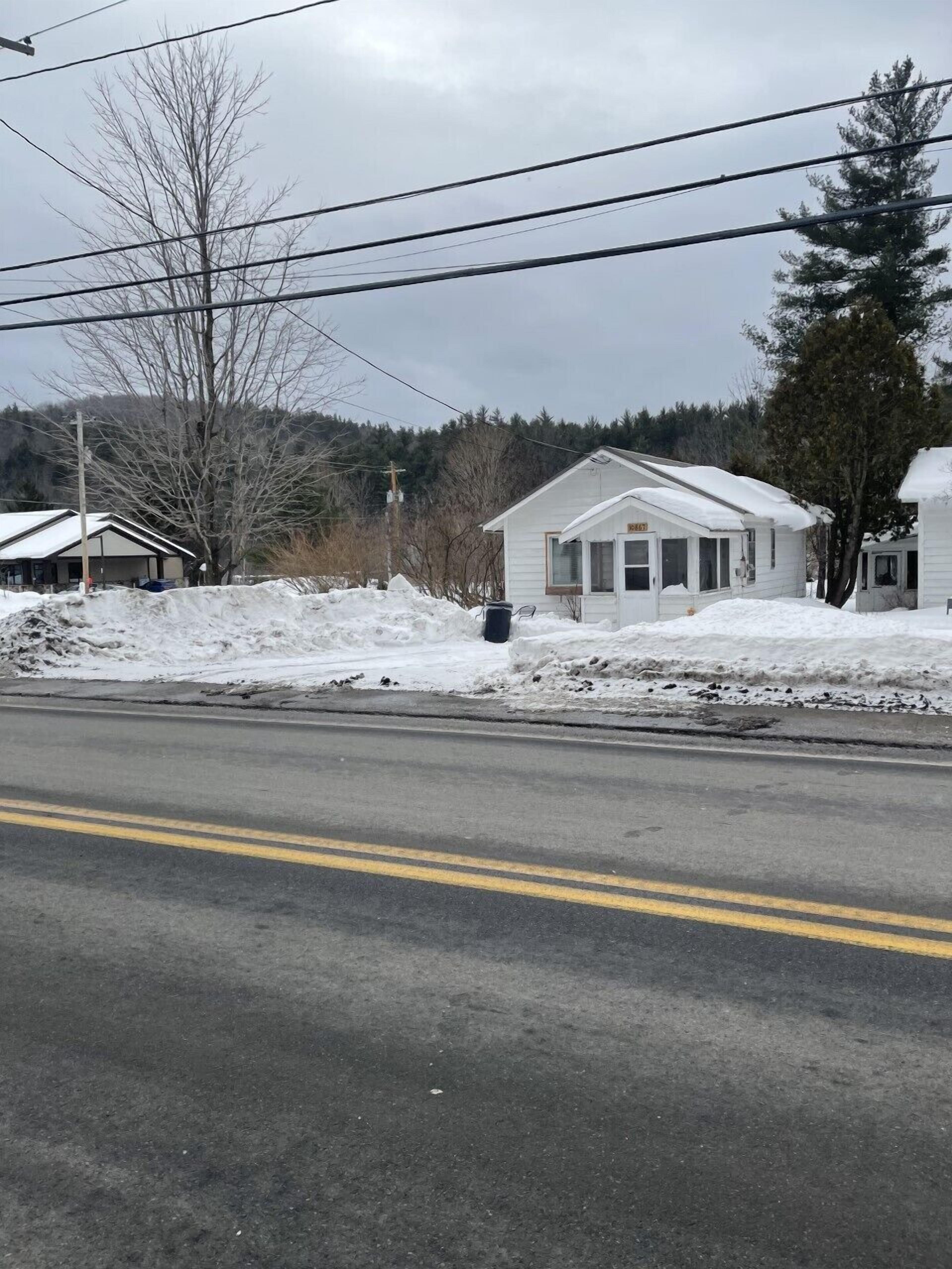 A small, single-story house with a snow-covered roof and a garage.