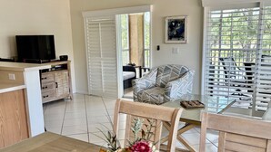 A living room with a TV, a sofa, a dining table with chairs, and a window with blinds. - Golf Lovers' Haven in PGA Village  (Port St Lucie)