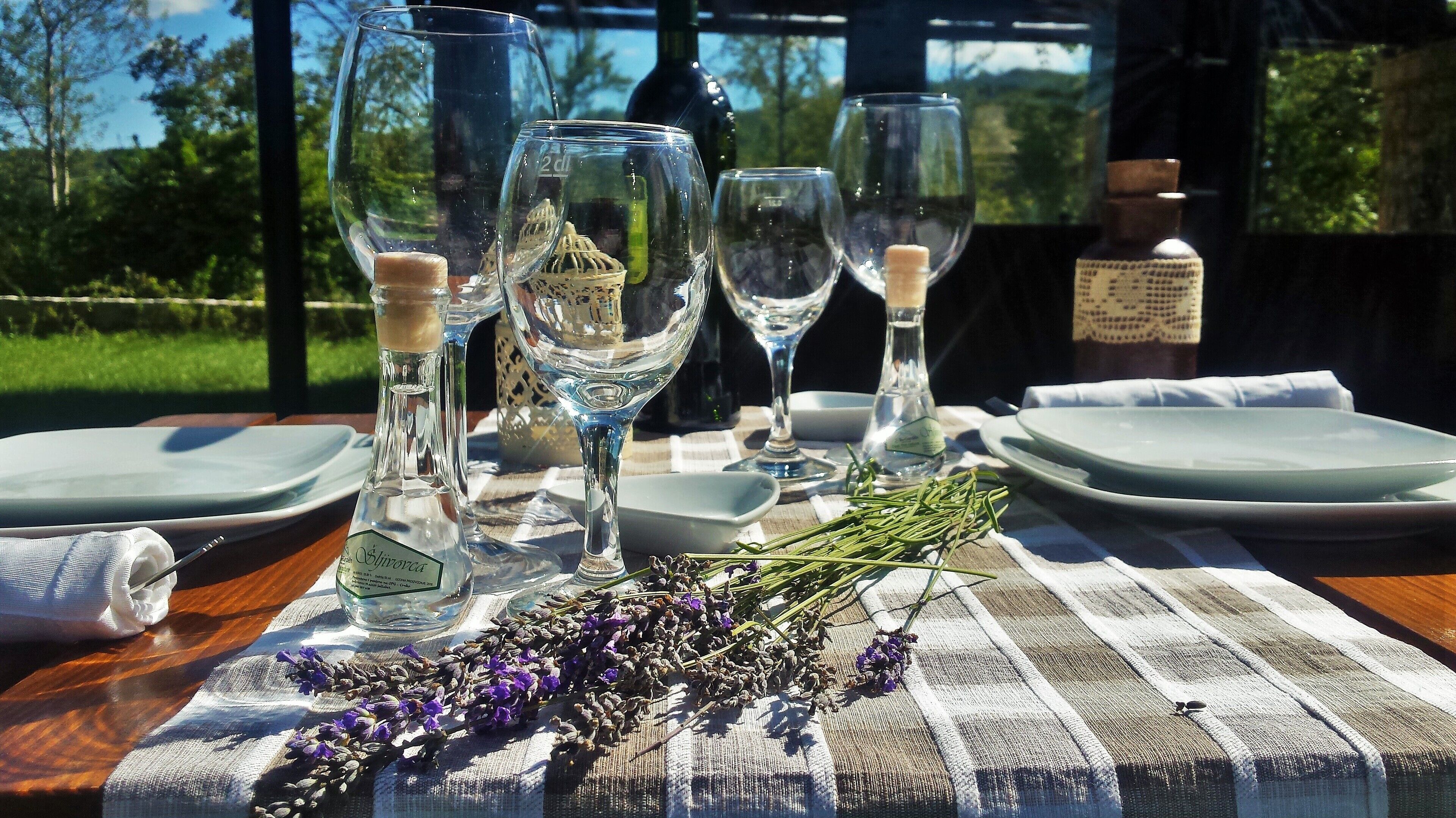 A table set for a meal with wine glasses, a bottle, and a bottle of water.