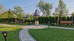 Un chemin de pierres mène à un belvédère situé dans un jardin bien entretenu, où l’on trouve également une balançoire et un lampadaire.