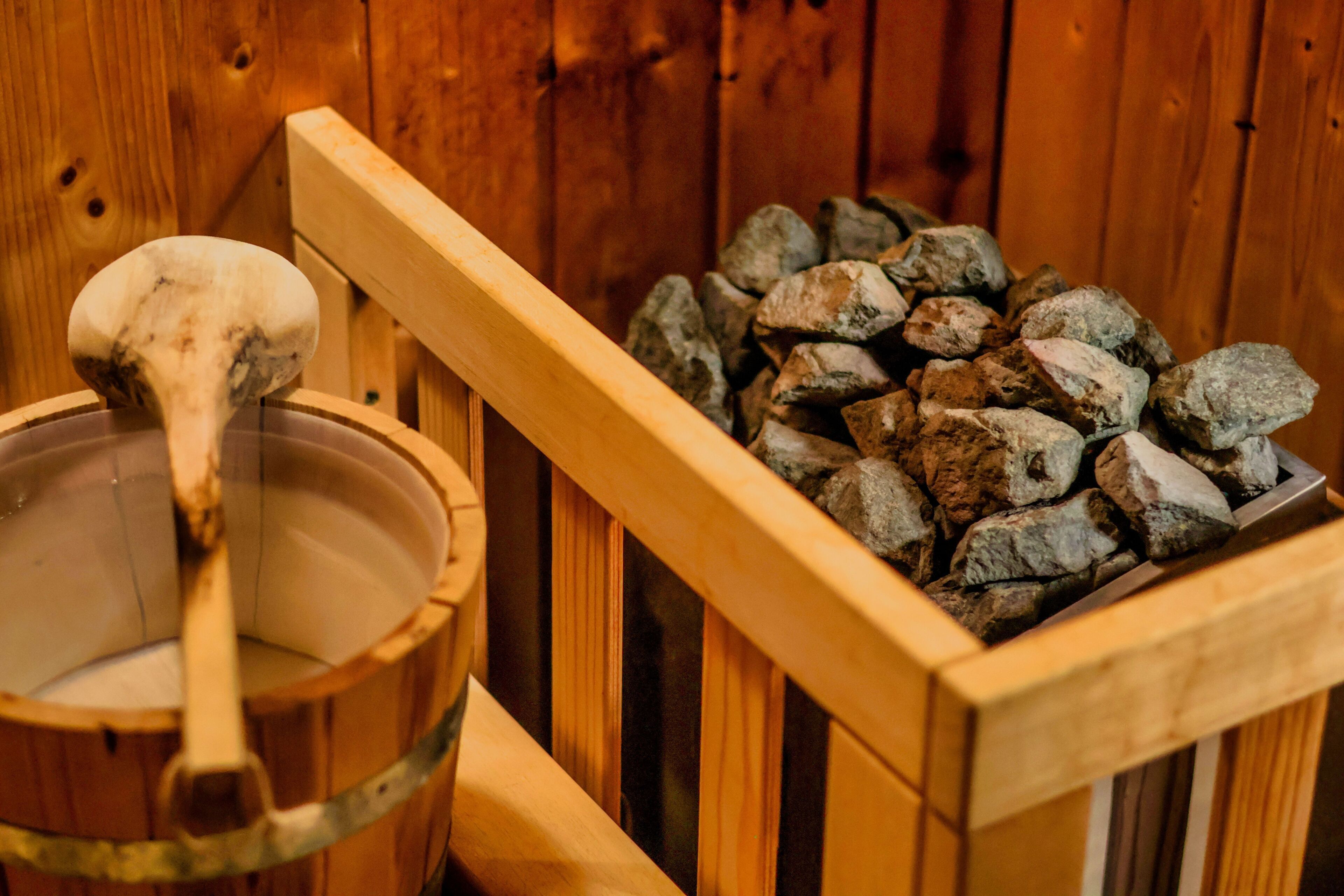 Una sauna de fusta amb una cullera de fusta i un grapat de pedres.