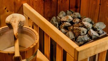 Una sauna de fusta amb una cullera de fusta i un grapat de pedres.