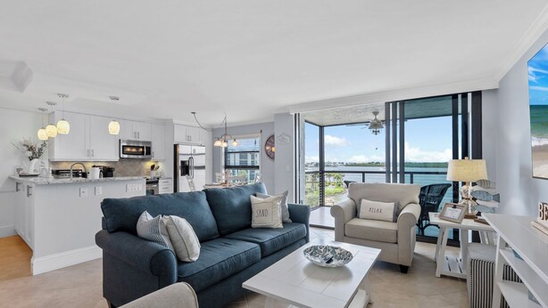 Una sala de estar moderna con un sofá azul, una mesa de centro blanca y vista al mar a través de amplios ventanales.