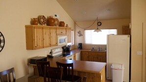 A compact kitchen with wooden cabinets, a microwave, a sink, and a refrigerator.