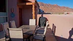 An outdoor patio with a table and chairs, a wooden pergola, and a mountain view.