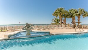 Une piscine agrémentée d’une sculpture de dauphin, de palmiers et offrant une vue sur l’océan.