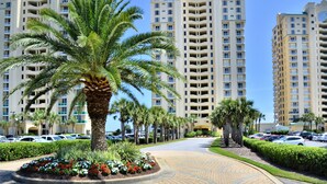 Un quartier résidentiel avec de grands immeubles d’appartements, des palmiers et une promenade dallée.