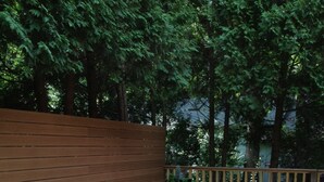 An outdoor seating area with green chairs and a white table, surrounded by a wooden deck and a wooden fence. - 300 paces-1/2 Block to McKinley Beach, Fire Pit, Screened Gazebo,
Outdoor Shower (Union Pier)