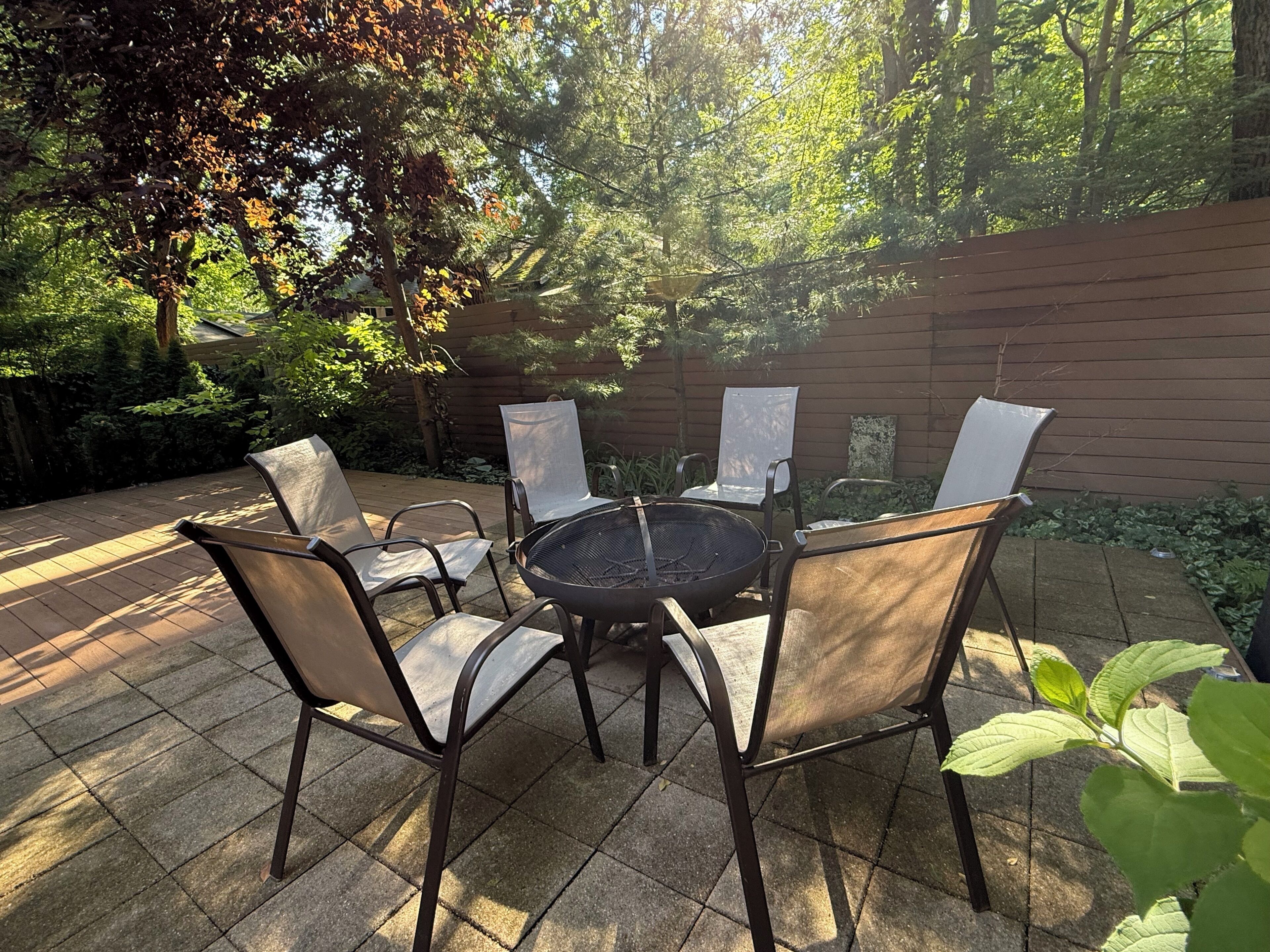 A patio with a round table and chairs, surrounded by a brick wall and greenery.