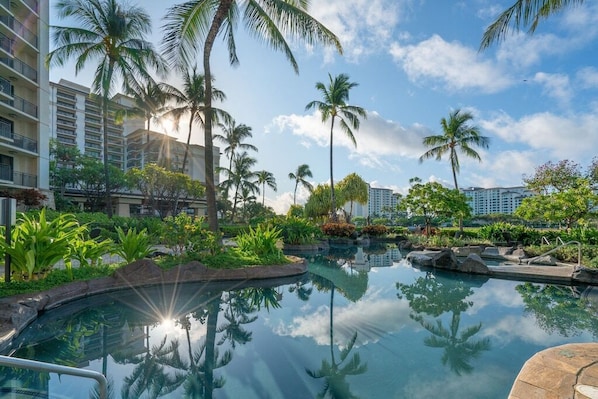 Piscina de hotel con palmeras y cielo despejado.