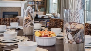 A dining table set with white bowls, plates, and a centerpiece of seafood and corn.