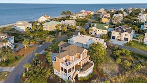 A coastal residential area with houses, a beach, and a clear sky.