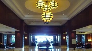 A spacious lobby with a central fountain, a chandelier, and a view of the outdoors through large windows.