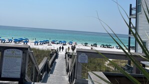 A wooden boardwalk leading to a beach with umbrellas and people. - MERMAID - Largest Heated Pool, Walk to Private Beach, GolfCart, Pet Friendly. (Miramar Beach)