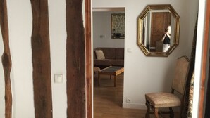 Une pièce avec des poutres apparentes, un lit, une chaise et un miroir au mur.