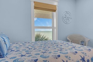 A bedroom with a large bed, a wicker chair, a window with a view of the beach, and a compass wall decoration. - Rx: Paradise updated 2bed/2.5bath townhouse style condo with open water views, shared pool & dockage (Marathon)