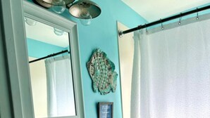 A bathroom with a white toilet, a sink, a mirror, and a shower curtain.
