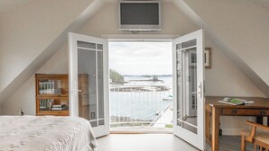 A bedroom with a large window, a bed, a desk, and a television. - Timeless Days, Oceanfront Fisherman’s Cottage, Deep Water Dock & Boathouse (Port Clyde)