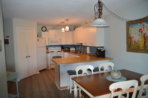 Une cuisine avec des meubles blancs, un îlot central en bois et une table à manger avec des chaises.