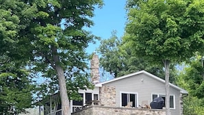 Ein Steinhaus mit Schornstein, umgeben von Bäumen.