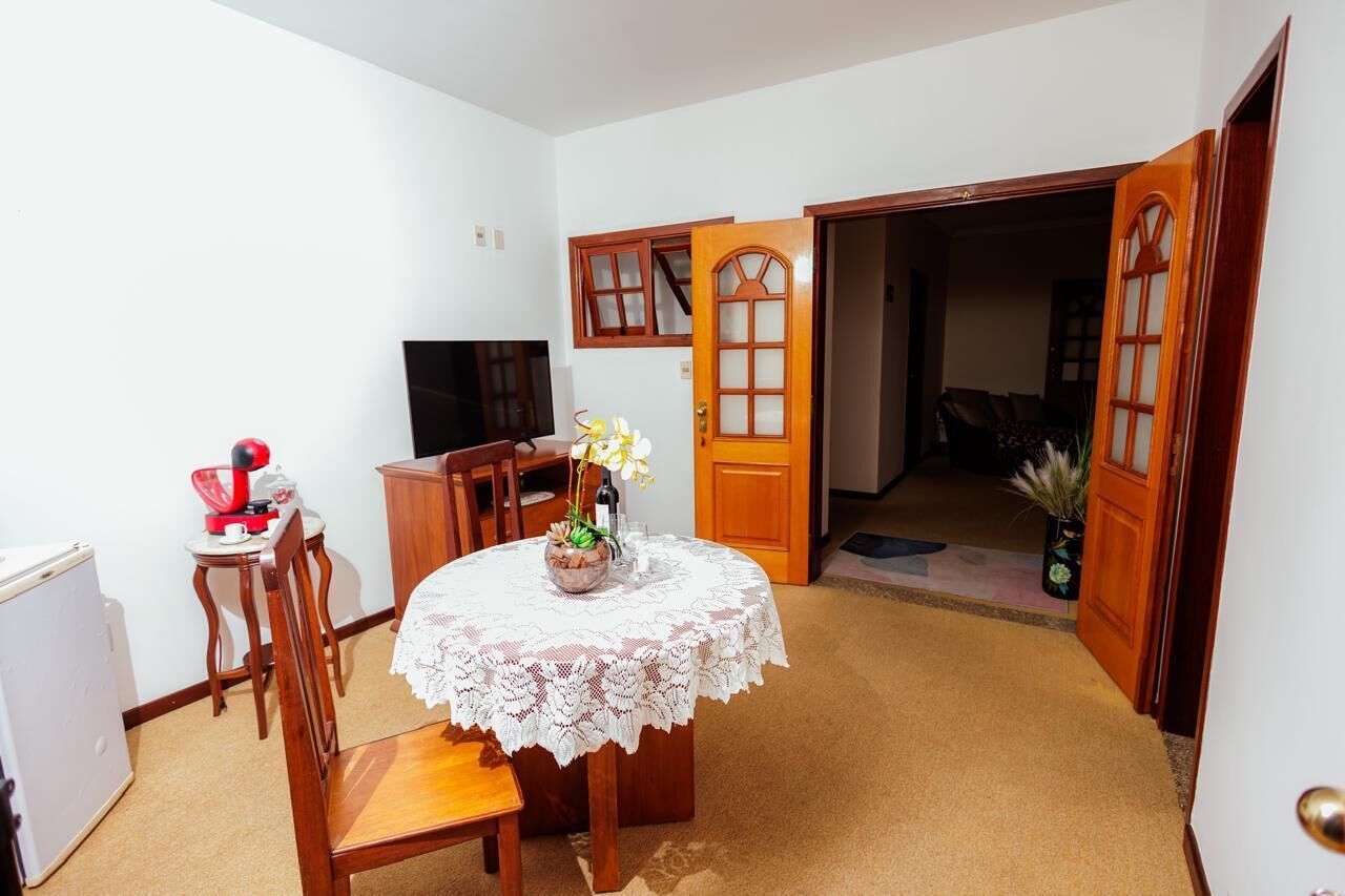 A dining area with a round table, chairs, a television, and a door leading to another room.