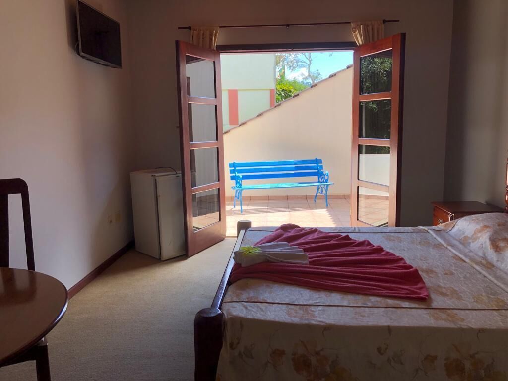 A bedroom with a bed, a desk, a chair, and a small refrigerator.