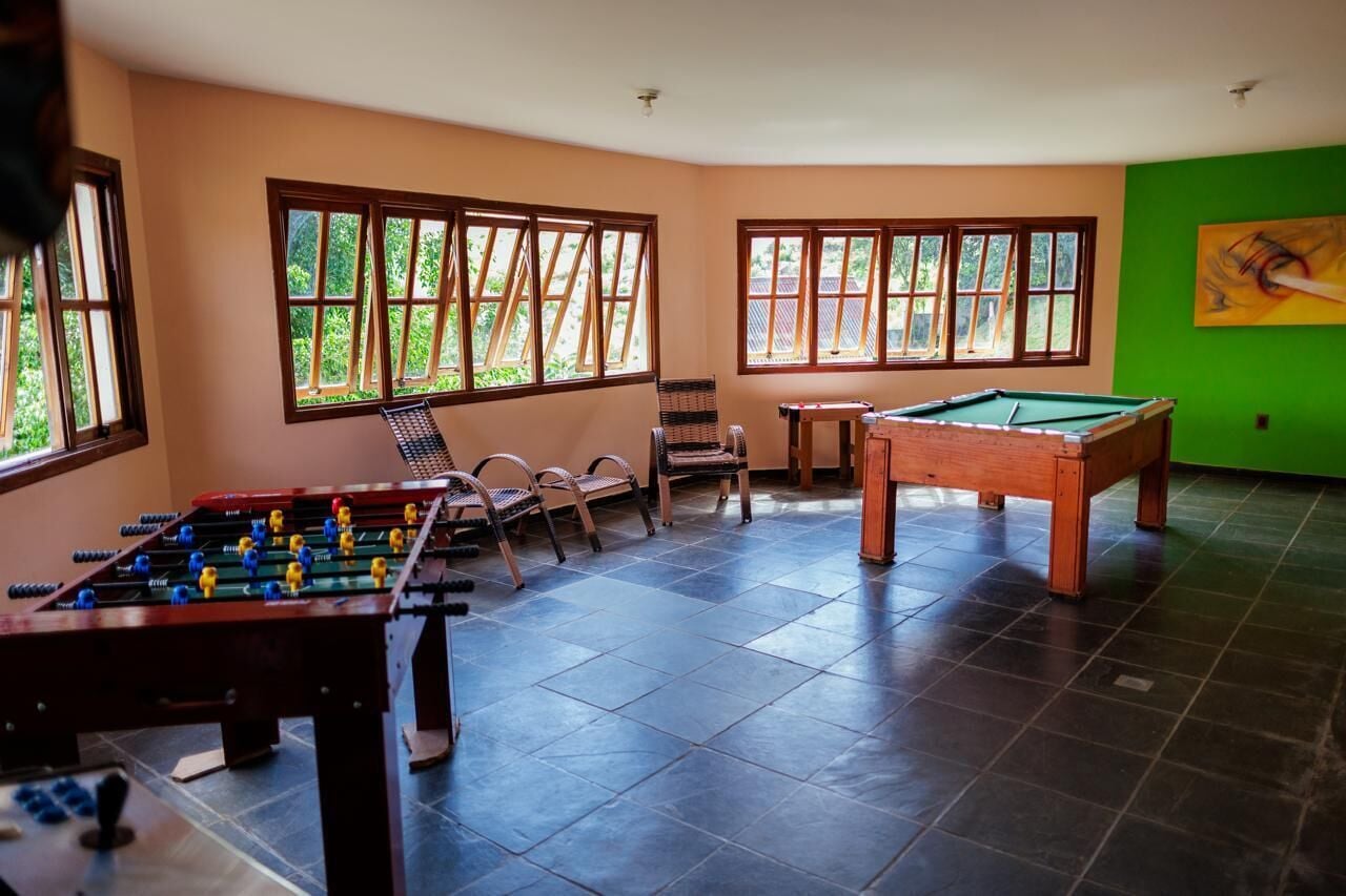 Una habitación con mesa de fútbol, mesa de billar y sillas de mimbre.