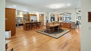 Una cocina amplia con armarios de madera, una isla central y un comedor con candelabro.
