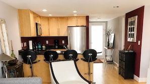 A modern living room with a grey sofa, a white armchair, a coffee table, and a colorful striped rug. - Stay in the Heart of Dewey: Beach, Pool & Fun at Your Doorstep (Dewey Beach)