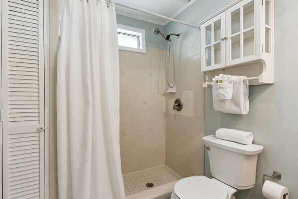 Ein Badezimmer mit Dusche, Toilette und einem Schrank mit Handtüchern.