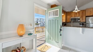 Een moderne keuken met een groene deur, witte muren en houten kastjes.