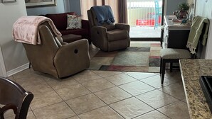 Een woonkamer met een bruine leren bank, een fauteuil en een eethoek met een granieten aanrecht.