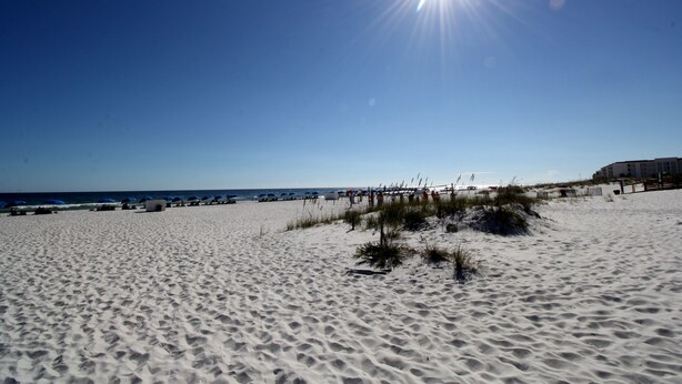 Een zandstrand met een heldere lucht en de zon.