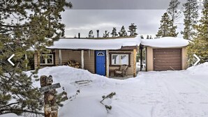 A cabin with a snow-covered roof, a blue door, and a wooden exterior.