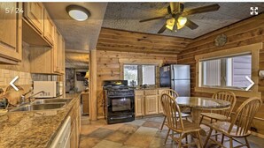 A kitchen with wooden cabinets, granite countertops, a stove, refrigerator, and a dining area with chairs.