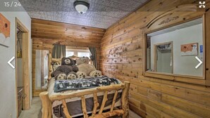A wooden cabin bedroom with a bed, pillows, and a mirror.