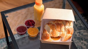 Una mesa de vidrio con una caja de pan y una botella de jugo.