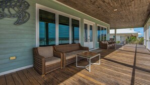 A covered porch with wicker furniture and a view of the ocean. - 🌊 The Great Escape | Sleeps 22 w/ Gulf Views, Private Pool, + Crow's Nest 🏖️ (Pensacola Beach)