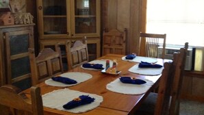 Ein Esszimmer aus Holz mit einem großen Tisch, gedeckt für sechs Personen, umgeben von Holzstühlen.