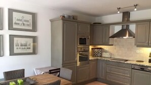 Una cocina moderna con armarios grises, una mesa de comedor con sillas y un piso de baldosas.