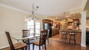 A spacious kitchen with wooden cabinets, a dining area with a glass table and chairs, and a bar area with stools. - Private 3 Acre Home North Nashville (Goodlettsville)