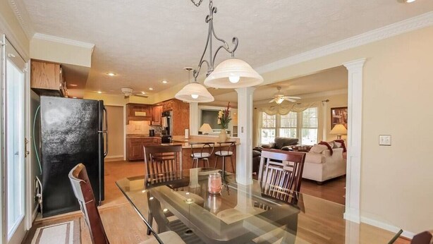 A spacious kitchen with a glass dining table, wooden chairs, and a black refrigerator. - Private 3 Acre Home North Nashville (Goodlettsville)