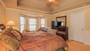 A bedroom with a large bed, a ceiling fan, a television, and a dresser. - Private 3 Acre Home North Nashville (Goodlettsville)